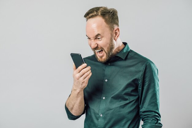 Portrait d'un homme en colère criant dans le haut-parleur de son smartphone