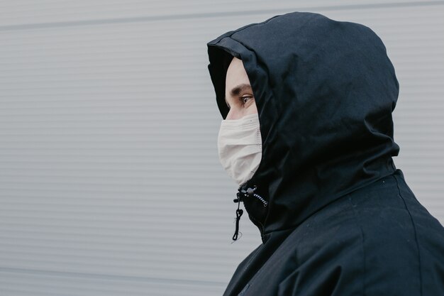 Portrait d'un homme dans un masque chirurgical sur fond d'un immeuble moderne.