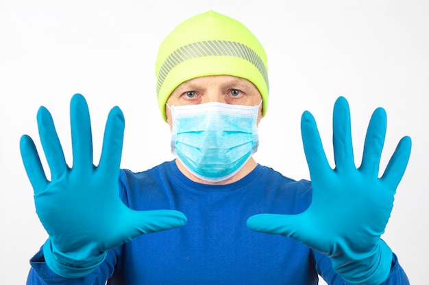 Portrait d'un homme dans un masque médical avec les mains levées dans des gants de protection