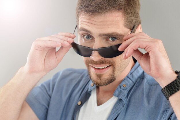 Portrait d'homme dans un style décontracté posant dans des lunettes de soleil