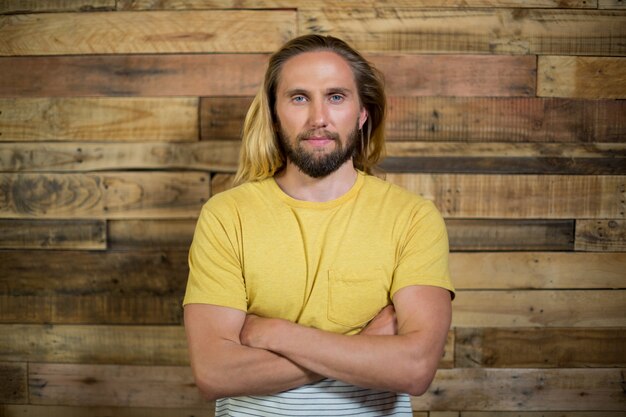 Portrait d'homme debout avec les bras croisés contre le mur en bois