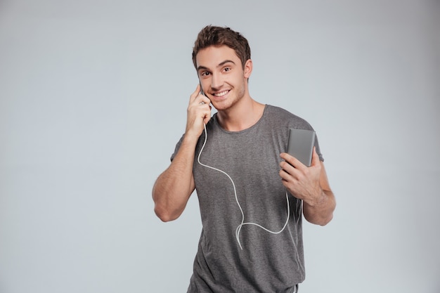 Portrait d'un homme décontracté souriant parlant au téléphone portable et le chargeant isolé sur blanc