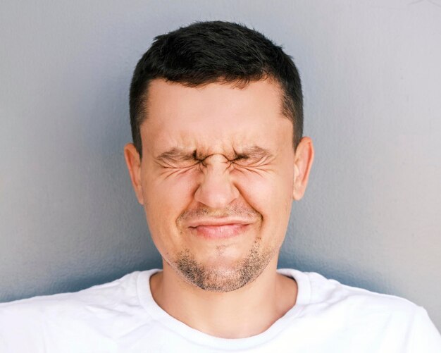 Portrait d'un homme drôle avec du chaume fermer les yeux et souriant sur un fond clair une émotio