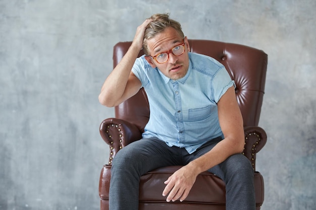 Portrait d'un homme élégant et intelligent regarde dans l'appareil photo petite chemise bleu charismatique mal rasé s