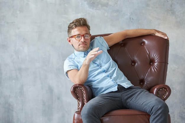 Portrait d'un homme élégant et intelligent regarde dans l'appareil photo petite chemise bleu charismatique mal rasé s