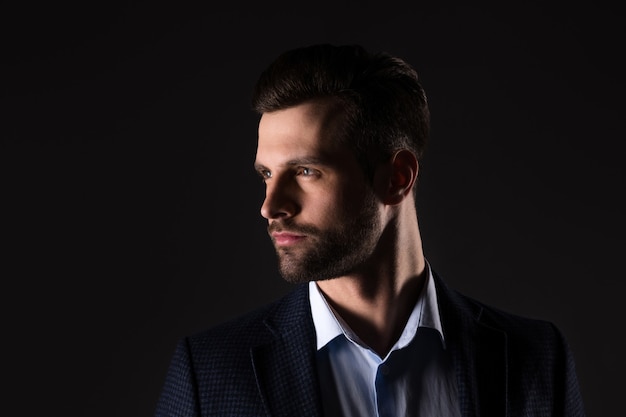 Portrait d'un homme élégant et séduisant portant une veste isolée sur fond de couleur noir foncé