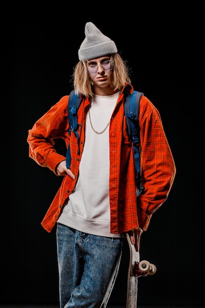 Portrait d'un homme élégant tenant une planche à roulettes dans le Studio Gros plan d'un skateur souriant posant sur un fond noir