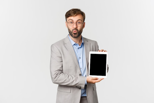 Portrait d'homme entrepreneur barbu étonné en costume gris et lunettes