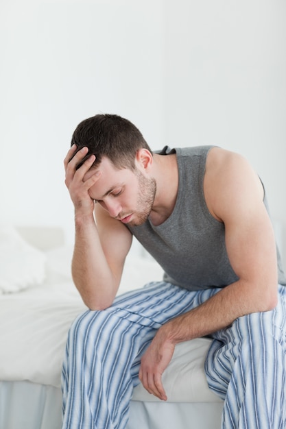 Portrait d&#39;un homme épuisé assis sur son lit