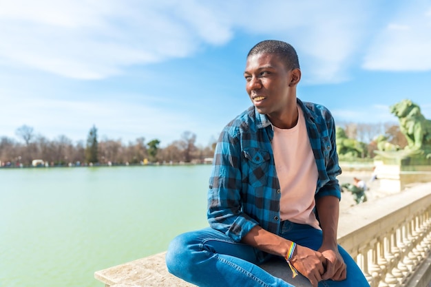 Portrait d'un homme ethnique noir en été au bord d'un lac, profitant sans souci des vacances d'été