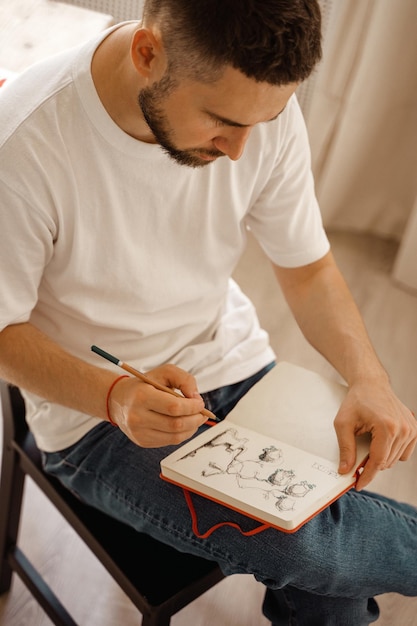 Photo portrait d'un homme faisant un croquis au crayon l'artiste s'assied sur une chaise et fait un croquis atelier créatif mode de vie le processus de création d'une œuvre d'art la recherche d'inspiration