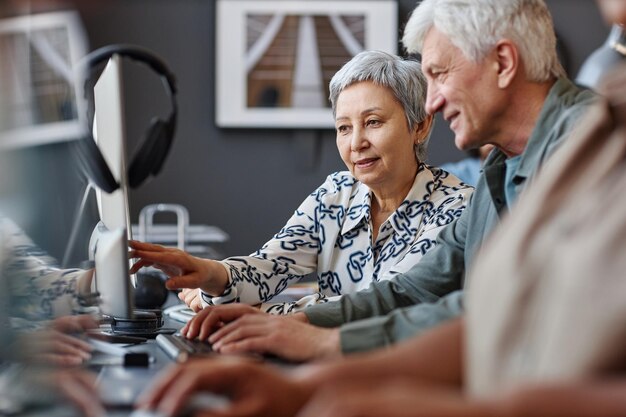 Photo portrait d'un homme et d'une femme âgés regardant un écran d'ordinateur dans un cours de technologie pour les personnes âgées