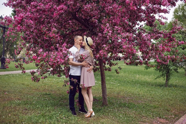 Portrait homme et une femme amoureuse se tiennent près d'un cerisier rose en fleurs en été