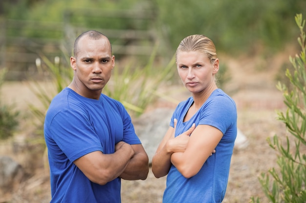 Portrait d'homme et femme en forme debout avec les bras croisés pendant la formation du camp d'entraînement