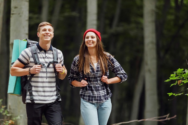 Portrait d'un homme et d'une femme qui ont l'air heureux tout en voyageant ensemble en montée dans la forêt