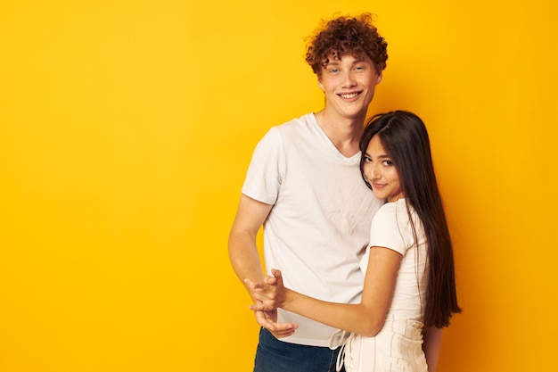 Portrait d'un homme et d'une femme se serrant l'un contre l'autre en t-shirts blancs fond jaune inchangé