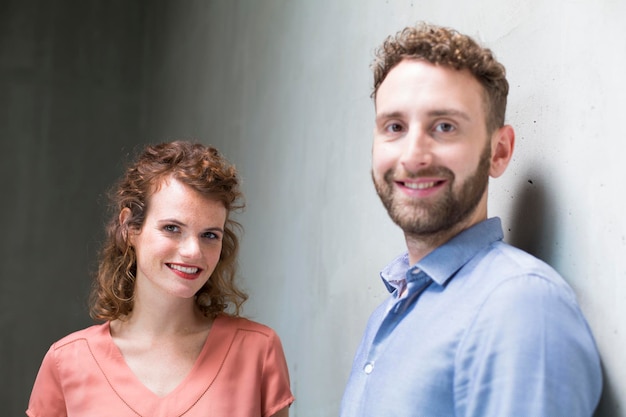 Portrait d'un homme et d'une femme souriants au mur de béton