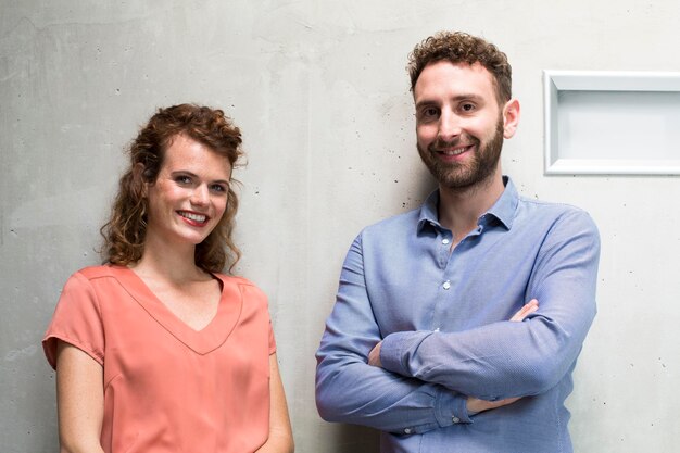 Portrait d'un homme et d'une femme souriants au mur de béton