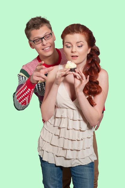 Portrait d'un homme et d'une fille avec un gâteau sur fond isolé pastel vert. Mignon attrayant drôle drôle positif fou. Fermer.