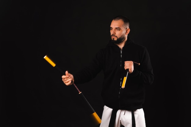 Le portrait d'un homme fort sérieux exécute quelques exercices avec son nunchaku