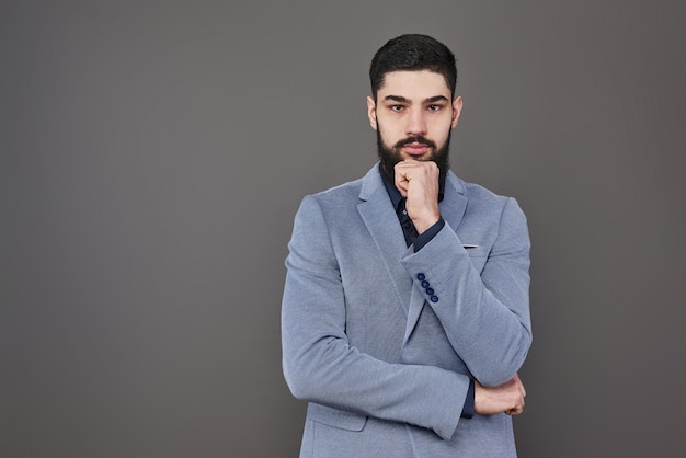 Portrait d'homme freelance avec barbe en veste debout sur fond gris