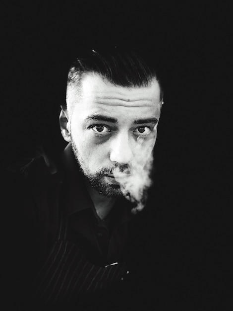 Photo portrait d'un homme fumant sur un fond noir