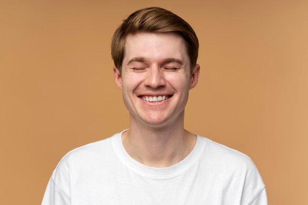 Portrait d'un homme gai heureux souriant à pleines dents avec les yeux fermés