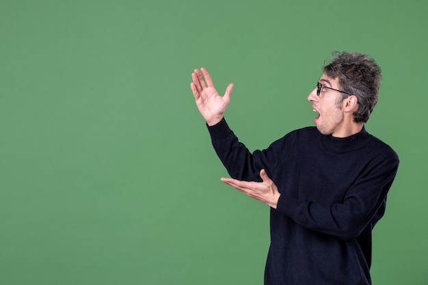 Portrait d'un homme de génie habillé avec désinvolture en studio tourné sur un mur vert