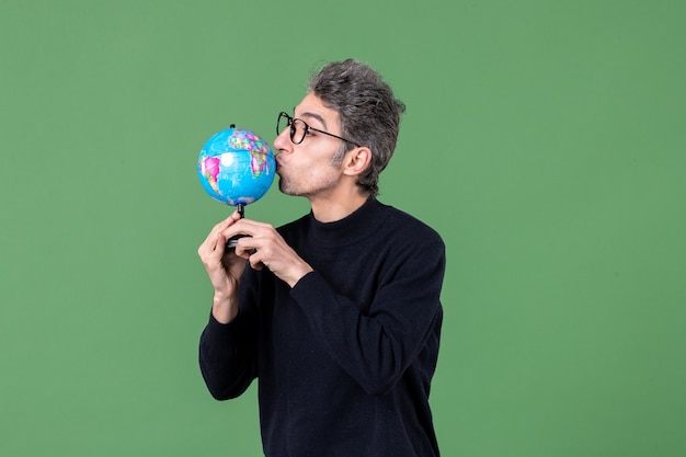 Portrait d'un homme de génie tenant un globe terrestre tourné en studio fond vert air mer espace professeur école nature planète