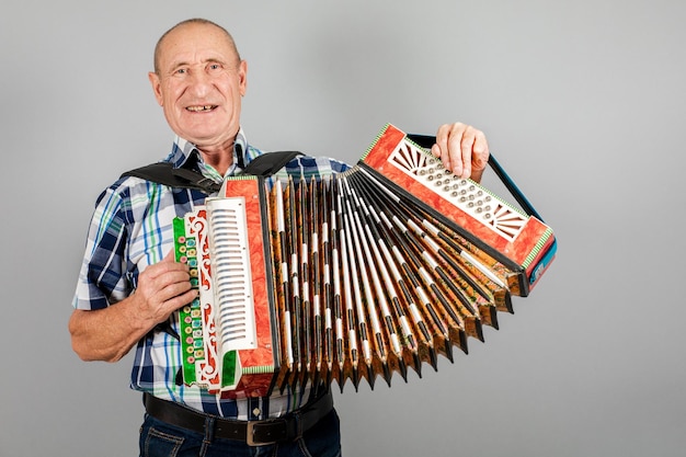 Portrait d'un homme grand-père joue de l'accordéon sur fond gris