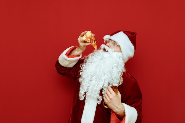 Portrait homme habillé en père Noël tenant la pizza et la bière