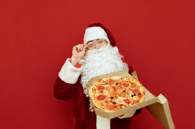 Portrait homme habillé en père Noël tenant une pizza