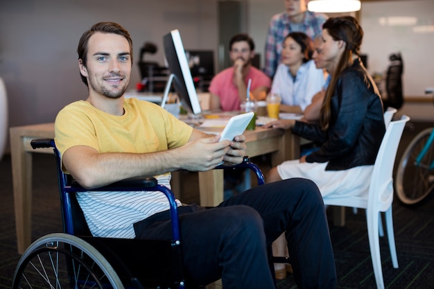 Portrait d'homme handicapé physique sur fauteuil roulant à l'aide de tablette au bureau