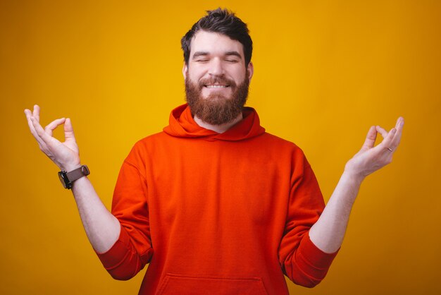 Portrait d'homme heureux méditant sur mur jaune