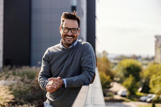 Portrait d'un homme heureux posant à l'extérieur dans le quartier financier et souriant à la caméra