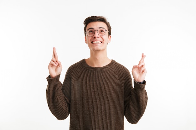 Portrait d'un homme heureux en pull tenant les doigts croisés