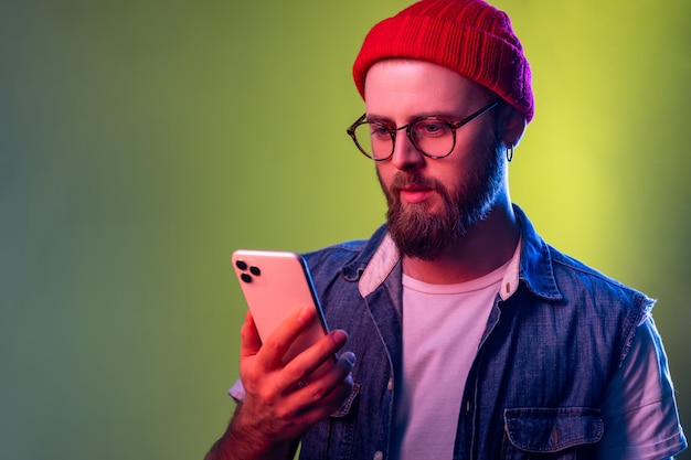 Portrait d'un homme hipster sérieux et affirmé tapant sur un smartphone pariant à l'aide d'une application en ligne