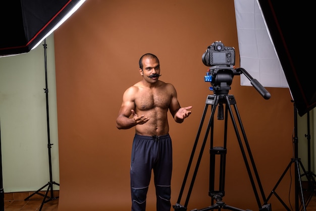 Portrait d'homme indien musclé avec moustache torse nu vlog avec appareil photo