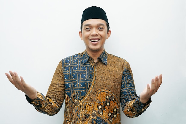 Portrait d'un homme indonésien asiatique en chemise traditionnelle Batik faisant des gestes pour présenter quelque chose