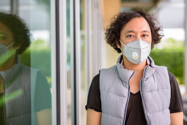 Portrait D'un Homme Japonais Aux Cheveux Bouclés Portant Un Masque Pour Se Protéger Contre L'épidémie De Coronavirus Dans La Ville à L'extérieur