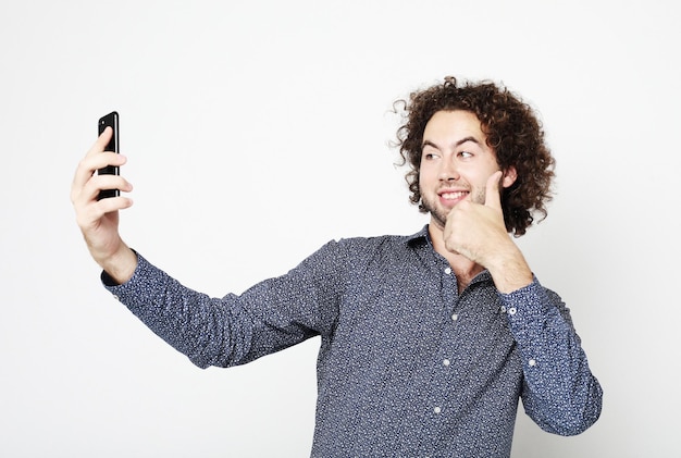 Portrait d'un homme joyeux prenant selfie sur fond blanc