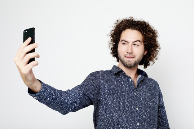 Portrait d'un homme joyeux prenant selfie sur fond blanc