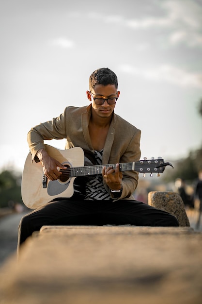 Portrait d'homme latin jouant de la guitare dans la rue pendant le coucher du soleil