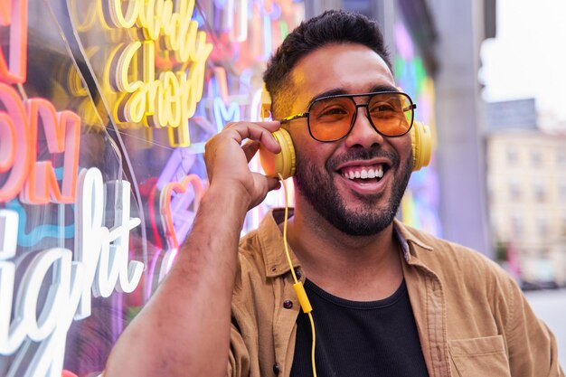 Portrait d'un homme latin souriant écoutant de la musique sur fond néon