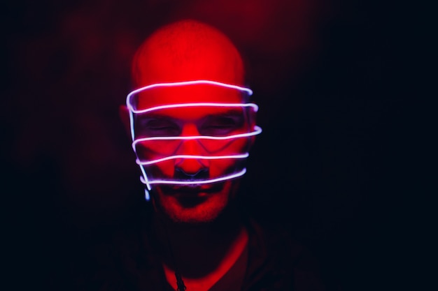 Portrait d'homme avec des lignes lumineuses au néon sur son visage. Concept cyberpunk et réalité virtuelle.