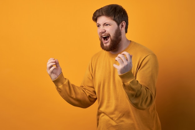 Portrait d'un homme mal rasé irrité énervé émotif serre les dents et fait des gestes avec colère tout en se disputant avec sa femme