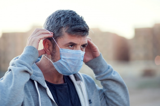 Un portrait d'homme avec masque facial médical en plein air. Concept de personnes, de soins de santé et de médecine