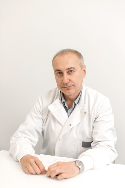 Portrait d'un homme médecin professionnel en blouse blanche assis à une table