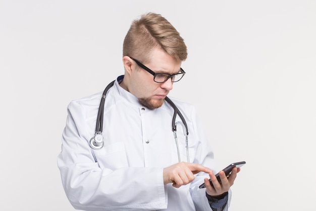 Portrait d'homme médecin avec smartphone en mains sur blanc