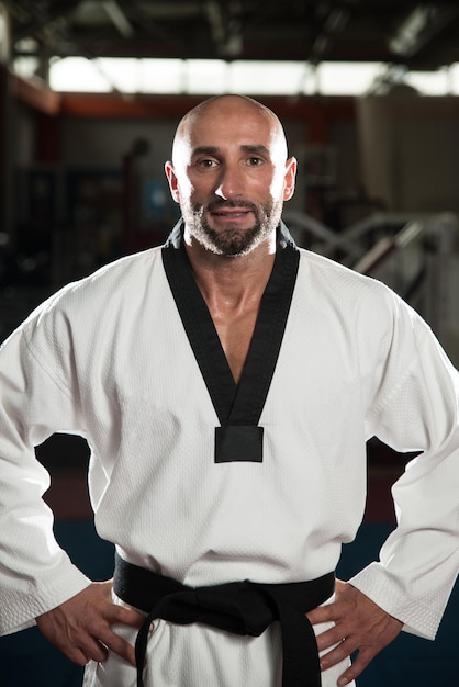 Portrait d'un homme mûr en bonne forme physique en kimono avec ceinture noire